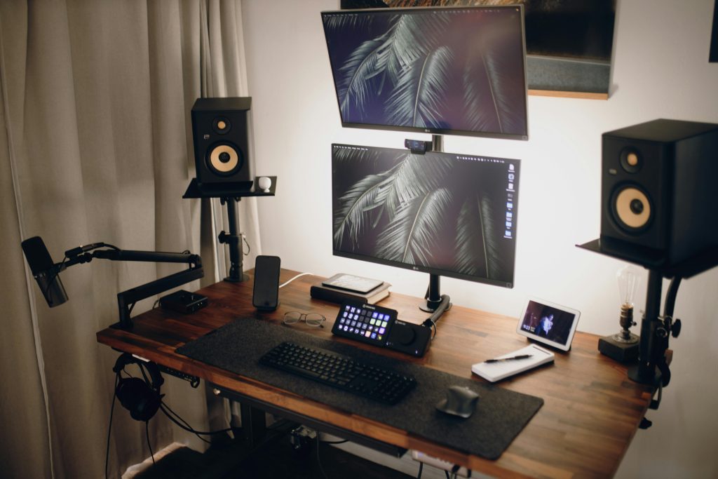 Contemporary streaming setup featuring dual monitors, speakers, and accessories on a wooden desk.