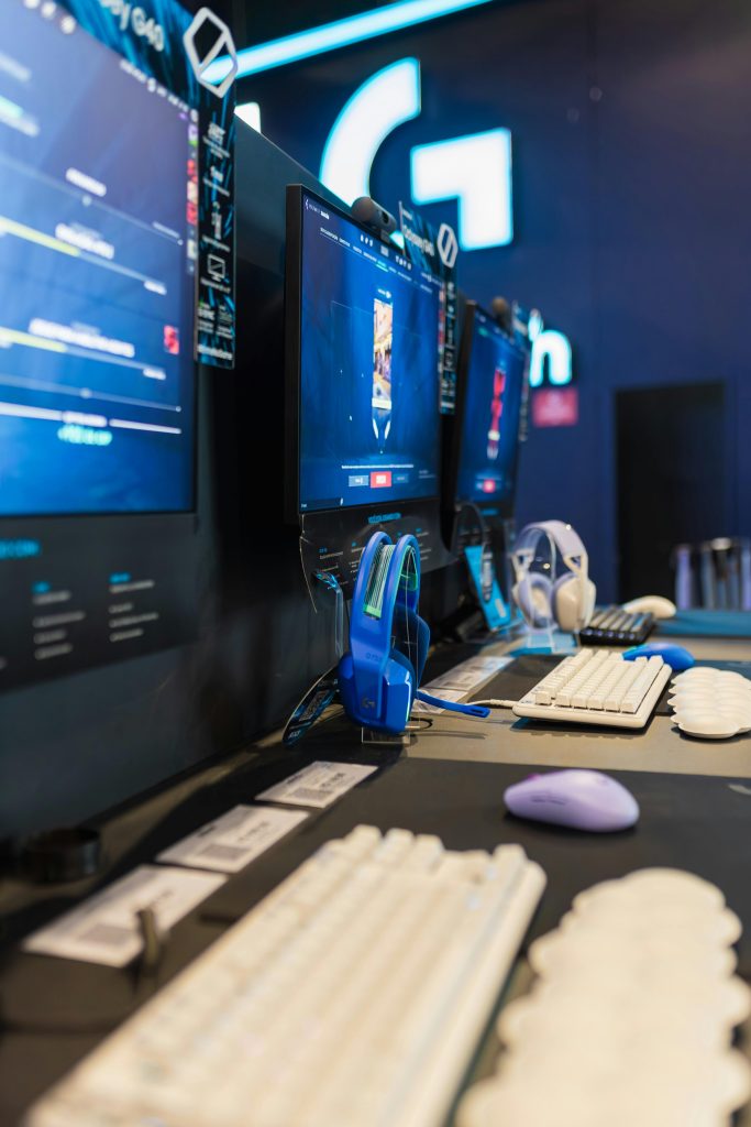 A contemporary gaming setup featuring multiple monitors, keyboards, and headphones in a vertical angle.